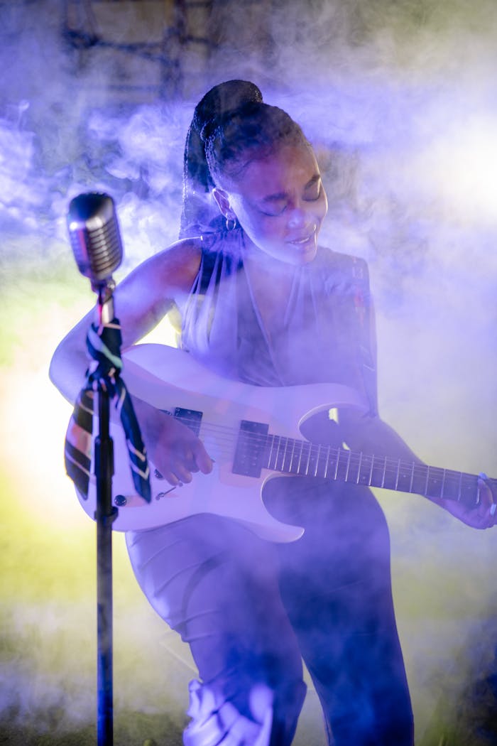 The Art of Drawing Readers In: Your attractive post title goes here A vibrant live performance featuring a skilled female guitarist amid colorful stage lighting and smoke.